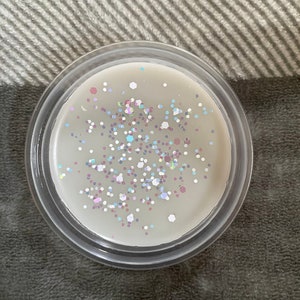 May include: A clear glass jar filled with white wax and iridescent glitter.