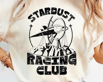 May include: Cream-colored t-shirt featuring a black graphic of a vintage airplane, a circular design, and the text "STARDUST RACING CLUB." The shirt has rolled-up sleeves and is paired with blue jeans.