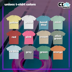 Op de afbeelding: Een display van unisex t-shirts in verschillende kleuren, waaronder geel, wit en rood. De afbeelding toont ook shirts in roze, cr&egrave;me en olijfgroen. Extra kleuren zijn ijsblauw, grijs, groen en oranje. De tekst "unisex t-shirt colors" staat bovenaan.
