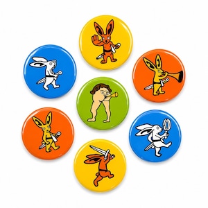 May include: Seven circular badges with cartoon rabbit illustrations. Each badge has a different design, with the rabbit figures in various poses, some holding knives or other items. The backgrounds are in blue, yellow, orange, and green.