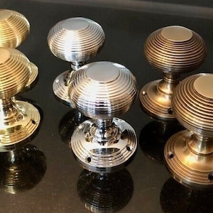 May include: Five door knobs with a ribbed design. Two are gold, two are silver, and one is a darker brass colour.