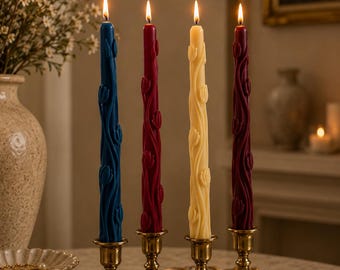 May include: Four tall, slender taper candles in blue, red, cream, and burgundy, each featuring a raised, embossed tulip floral pattern. The candles are lit, with visible flames, and are held in individual brass-toned metal candle holders.