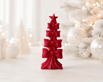 May include: A red wax candle shaped like a Christmas tree, featuring a star at the top and four stacked bows of increasing size from top to bottom. The candle has a smooth, matte finish and a single wick protruding from the center of the top star.