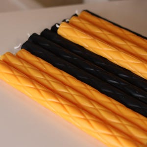 May include: A collection of long, slender taper candles arranged in alternating rows of bright yellow and solid black. Each candle features a distinct diamond-shaped lattice texture embossed along its entire length, finished with a white cotton wick.