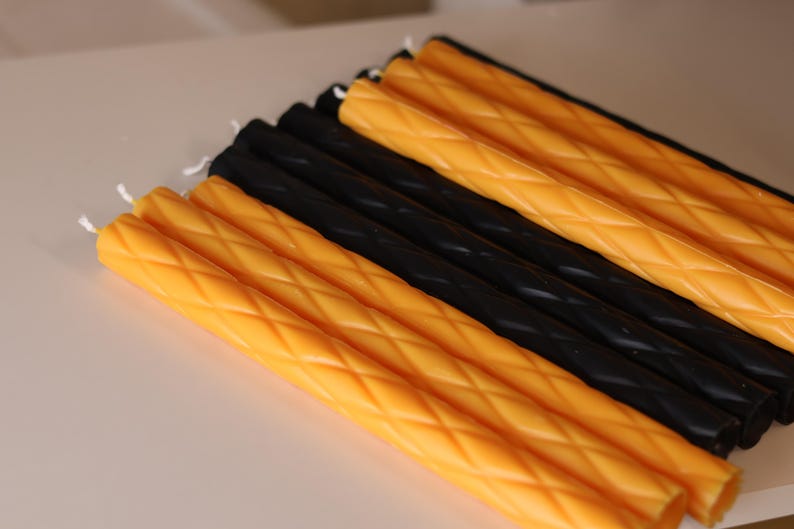 May include: A collection of long, slender taper candles arranged in alternating rows of bright yellow and solid black. Each candle features a distinct diamond-shaped lattice texture embossed along its entire length, finished with a white cotton wick.