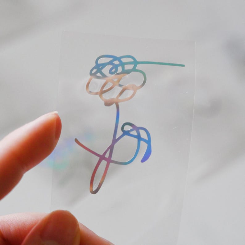 May include: A holographic sticker with a stylized flower design in shades of blue, pink, and purple.