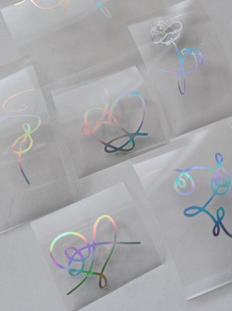 May include: A set of holographic stickers featuring different designs, including hearts, flowers, and abstract shapes. The stickers are on a clear background and are perfect for adding a touch of sparkle to any project.