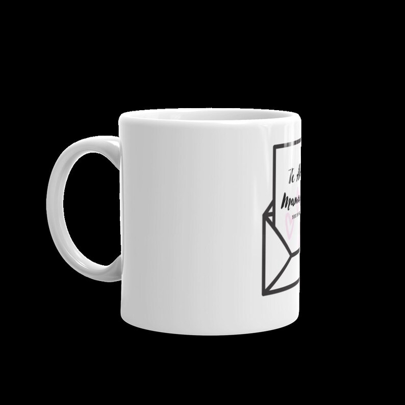 May include: White ceramic mug with a black and white illustration of an envelope with a handwritten note that says "To the Mom who..." with a pink heart.