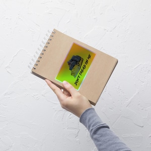 Op de afbeelding: Een sticker met een cartoon illustratie van een bulldozer en de tekst "DON'T TREAD ON ME". De sticker heeft een gele en groene gradiënt achtergrond. De tekst is vetgedrukt en sans-serif.