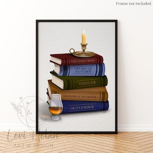 May include: A framed print featuring a stack of books with titles like "The Fiery Cross" and "Outlander." A lit candle sits atop the books, next to a glass of amber liquid. The artwork is set against a textured white background.