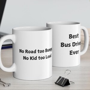 May include: Two white ceramic mugs with black text. The mug on the left says "No road too bumpy, No kid too loud". The mug on the right says "Best Bus Driver Ever".
