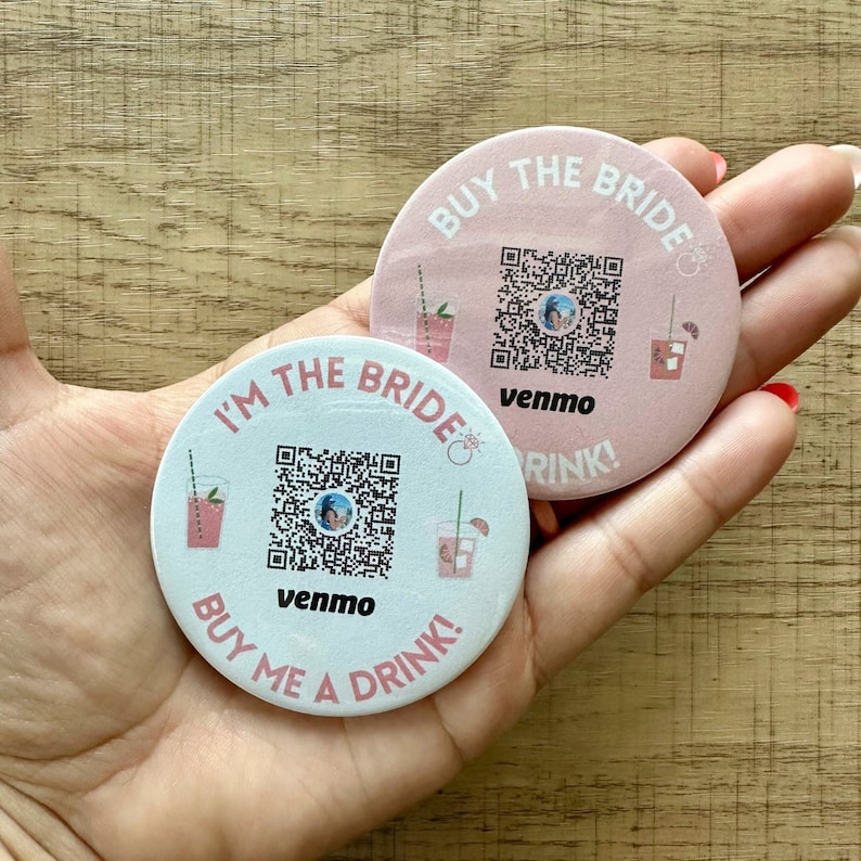 Peut inclure: Deux dessous-de-verre ronds en papier rose et blanc avec un code QR, le texte "BUY THE BRIDE" et "I'M THE BRIDE", ainsi que les mots "venmo" et "DRINK!" imprim&eacute;s dessus.