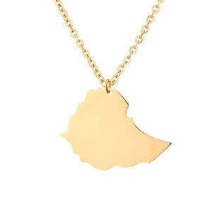 Puede incluir: Un collar dorado con un colgante con la forma del país de Etiopía. El colgante es liso y brillante, suspendido de una delicada cadena. El collar es una joya sencilla y elegante.