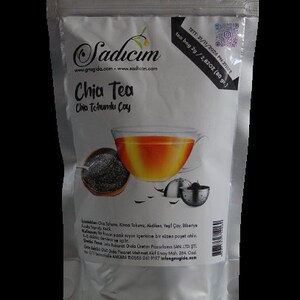 Puede incluir: Una bolsa plateada de pie con té Sadicim Chia Tea. La etiqueta muestra una taza de té, un cuenco con semillas de chía y un infusor de té de metal. El texto incluye 'Chia Tea', 'Chia Tohumlu Çay' y detalles del producto con 80 g.