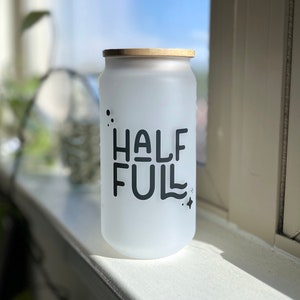 May include: A frosted glass jar with a wooden lid and the text "HALF FULL" printed in black.