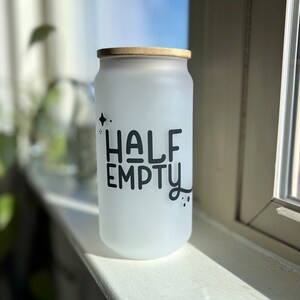 May include: White frosted glass jar with a wooden lid. The jar has black lettering that reads "HALF EMPTY".