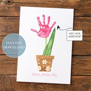 Puede incluir: Tarjeta del Día de la Madre imprimible con una flor de huella de mano rosa en una maceta con margaritas blancas. La tarjeta dice "Feliz Día de la Madre" e incluye una flecha que apunta a un espacio para una huella de mano con el texto "Añade tu huella de mano".