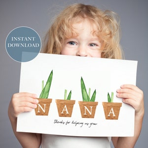 May include: A white card with the word "NANA" spelled out with green plants in brown pots. The text "Thanks for helping us grow" is written below the word "NANA". A child is holding the card in front of their face.