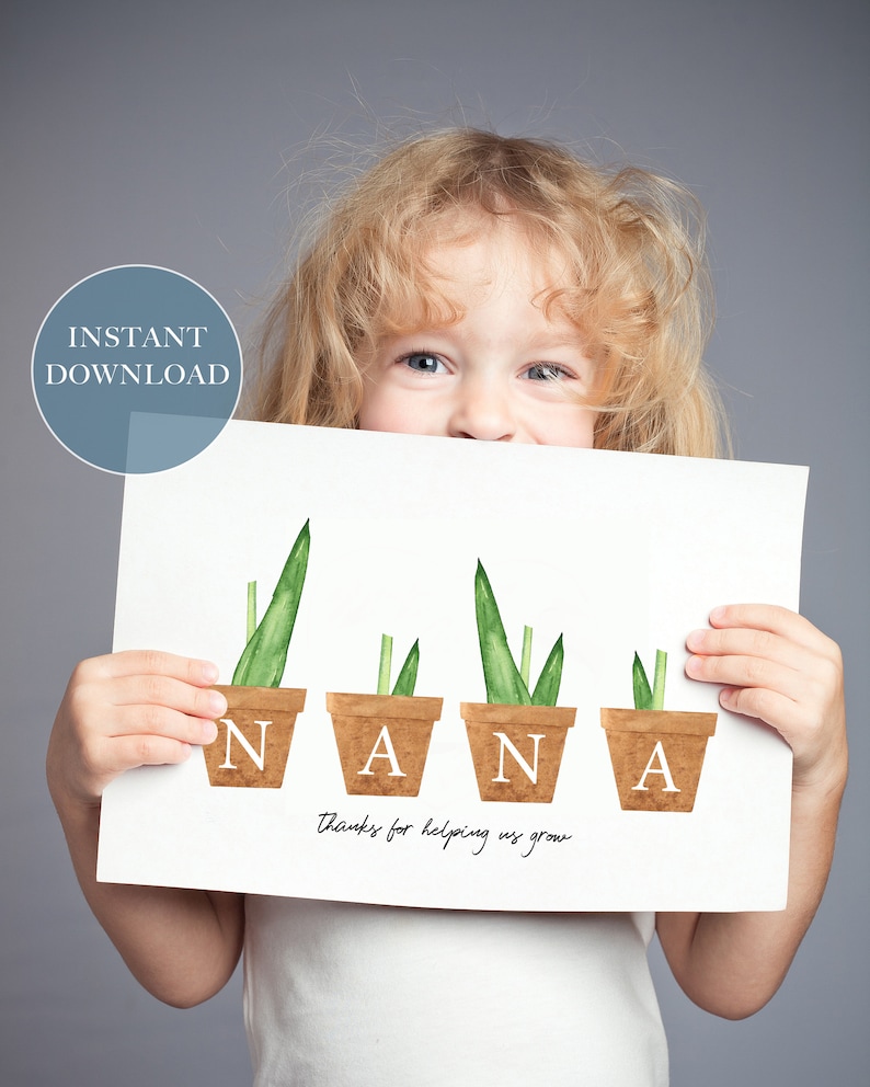 May include: A white card with the word "NANA" spelled out with green plants in brown pots. The text "Thanks for helping us grow" is written below the word "NANA". A child is holding the card in front of their face.
