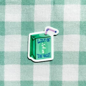 Puede incluir: Una caja de jugo de dibujos animados verde y blanca con una pajita rosa y el texto "Lily of the Valley".