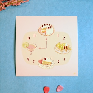 May include: A pink and white clock face with numbers 1 through 12. The clock face has four images: a slice of cake with berries, a glass of pink drink with a lime wedge, a plate of grapes and a slice of cake with berries, and a fork.