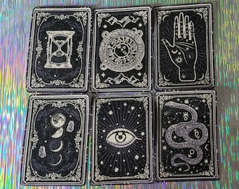 May include: Set of nine black and white tarot cards with ornate borders. The cards feature various symbols including an hourglass, a hand with stars, an eye, a snake, and a crescent moon.