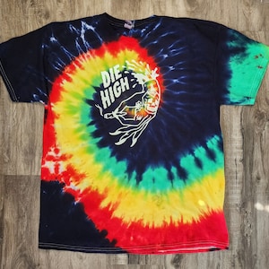 May include: A tie-dye t-shirt with a colourful swirl pattern in shades of red, yellow, green, and blue. The shirt features a white graphic of a skull with the text "DIE HIGH" above it.