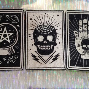 May include: Five black and white tarot cards with various occult designs. The cards feature a spider, a crystal ball with a star, a skull with a spiderweb, a hand with a skull, and a black cat with the text "THE BLACK CAT".