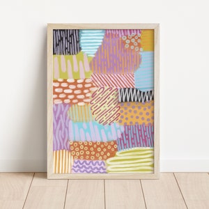 Peut inclure: Impression d'art abstrait avec un motif de patchwork coloré présentant diverses formes géométriques, lignes et motifs dans des tons de rose, violet, bleu, jaune, orange et marron. L'impression est encadrée dans un cadre en bois clair.