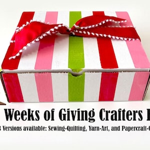 Puede incluir: Una caja de rayas rojas, blancas y verdes con una cinta roja y pompones blancos. La caja está etiquetada "4 Weeks of Giving Crafters Box" y "3 Versions available: Sewing-Quilting, Yarn-Art, and Papercraft-Cricut".