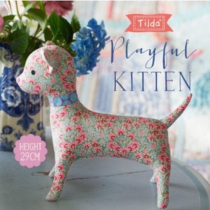 Puede incluir: Un patrón de costura Tilda Playful Kitten con un gatito de tela con estampado floral y un collar azul. El gatito mide 29 cm de alto.