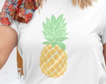 Pode incluir: Camiseta branca com um gráfico de abacaxi amarelo e verde. O abacaxi tem um topo verde e um corpo amarelo com um padrão de diamante.