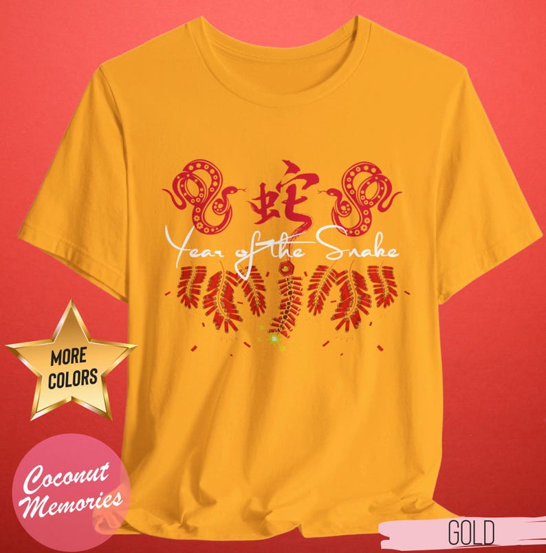 以下が含まれることがあります： 蛇の漢字と「蛇の年」の文字が書かれた、赤と白のデザインの黄色いTシャツ。