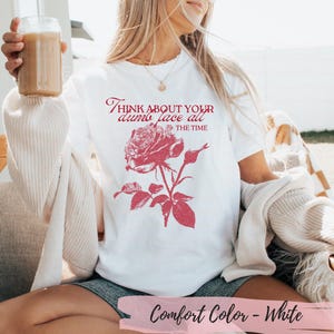 May include: White Comfort Color t-shirt featuring a red rose graphic with the text "Think About Your Dumb Face All The Time". The shirt has a crew neck and short sleeves. The bottom of the shirt has the text "Comfort Color - White".