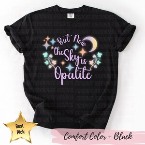 Pode incluir: Camiseta preta com a frase "But Now the Sky is Opalite" em uma fonte extravagante, cercada por estrelas e uma lua crescente. A camiseta também tem o texto "Comfort Color - Black" na parte inferior.