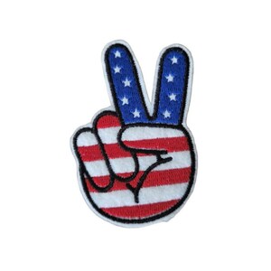 May include: A peace sign hand gesture with the American flag design. The hand is red, white, and blue with white stars on the blue fingers.