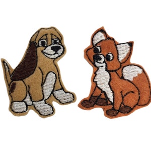 May include: Two embroidered felt patches, one of a brown and white dog and one of an orange and white fox. Both animals are sitting and looking to the right.