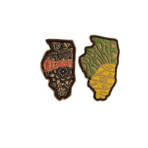 May include: Two embroidered patches shaped like the state of Illinois. One patch features a black and brown mandala design with the word "Illinois" in red. The other patch features a green and yellow design with the word "Illinois" in yellow.