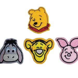 May include: Four embroidered iron-on patches featuring Winnie the Pooh, Piglet, Tigger, and Eeyore. The patches are yellow, pink, orange, and gray.