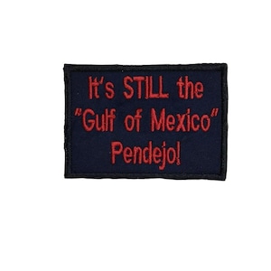 May include: A dark blue embroidered patch with red text that reads "It's STILL the "Gulf of Mexico" Pendejo!"