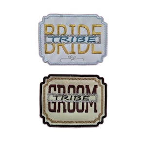 May include: Two embroidered patches, one white with gold lettering that says "Bride Tribe" and one beige with brown lettering that says "Groom Tribe".