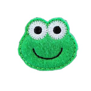 May include: Green felt frog applique with embroidered white eyes and a black smile.