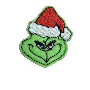 May include: Green Grinch character wearing a red and white Santa hat. The Grinch is frowning with a mischievous expression.