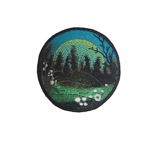 May include: Embroidered patch with a green, blue, and yellow landscape scene. The patch features a silhouette of trees, a yellow sun, and white flowers.