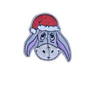 May include: Embroidered iron-on patch of a gray donkey wearing a red Santa hat with white trim. The donkey has purple ears and a stitched-on nose.