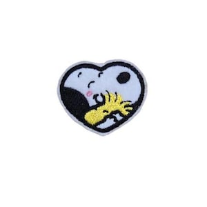 May include: Embroidered iron-on patch featuring Snoopy and Woodstock in a heart shape. Snoopy is white with black eyes and a black nose. Woodstock is yellow with black eyes.