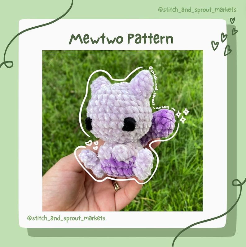 May include: A crocheted purple and white plush toy of the Pokemon Mewtwo. The toy is being held in a hand with a ring on the finger. The background is a blurry green.