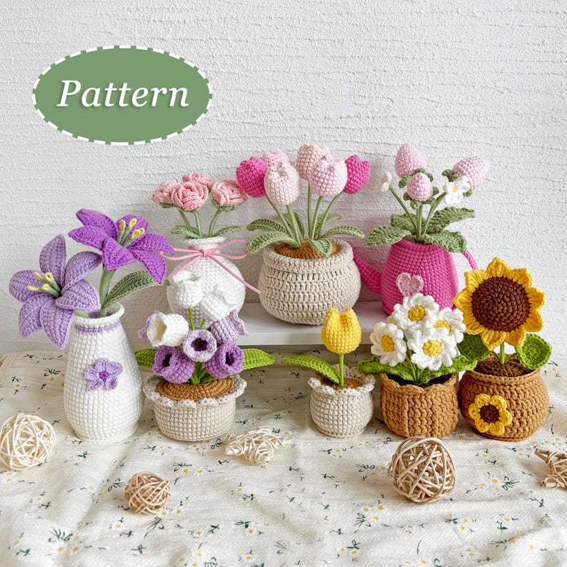 May include: A collection of handmade crochet flowers in various colors, including pink, purple, yellow, and white. The flowers are displayed in small pots and vases, with a sunflower and daisies. The word "Pattern" is in a green oval.