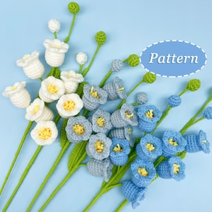 Peut inclure: Un bouquet de fleurs crochetées en blanc et bleu. Les fleurs sont disposées dans un vase et ont des tiges vertes. Les fleurs sont faites de laine et ont un aspect délicat et fait main. Le mot "Pattern" est écrit dans un cercle sur le fond.