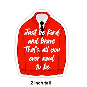 May include: A red cardigan sticker featuring a white shirt and black tie underneath. The text reads: Just be kind and brave That's all you ever need to be. The sticker is 2 inches tall and has a white border around the red garment design.